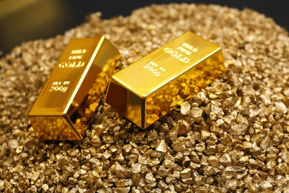 Shimmering gold bars resting on a bed of sparkling gold nuggets.