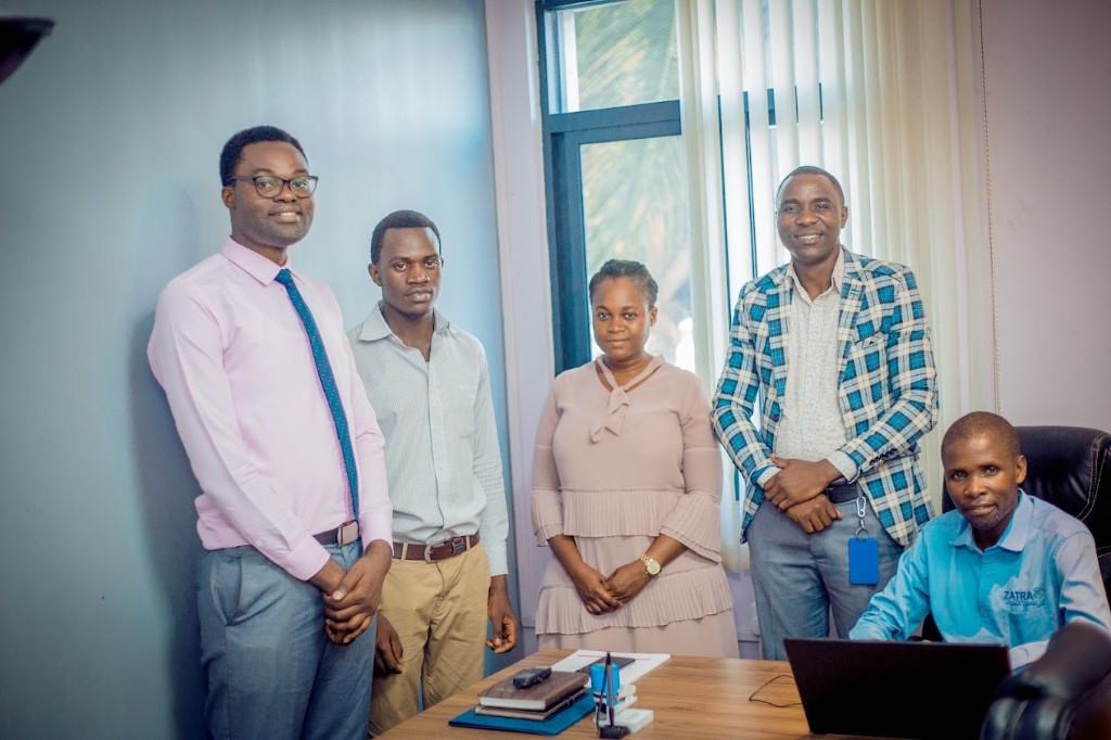 Zatra Consultants team gathered around a desk at the Dar es Salaam office.