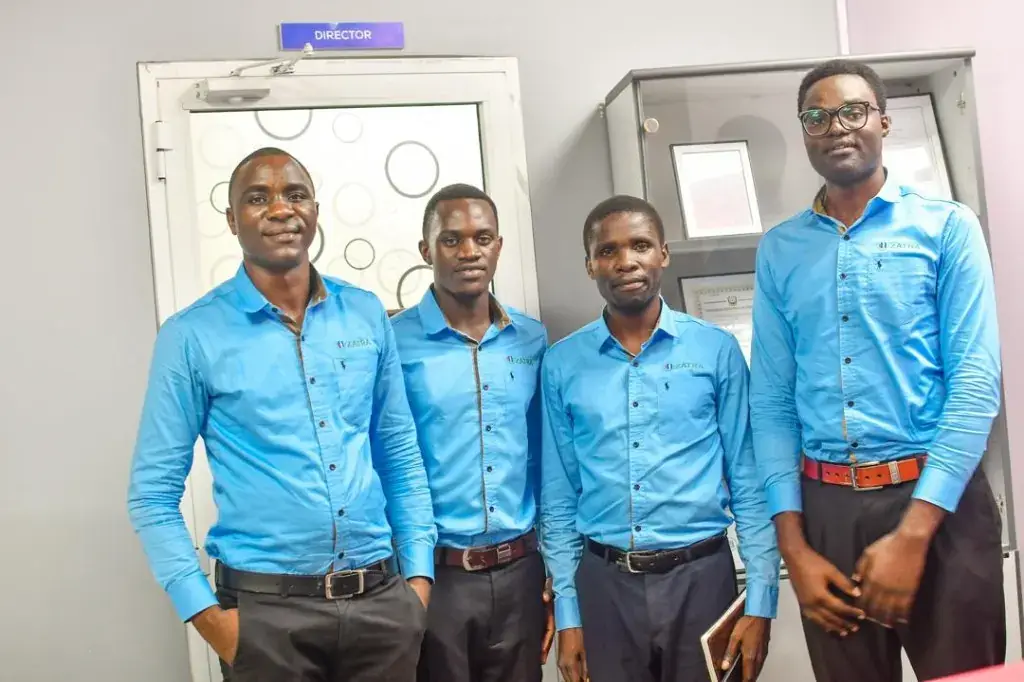 Four Zatra Consultants team members in branded shirts at the Dar es Salaam office.