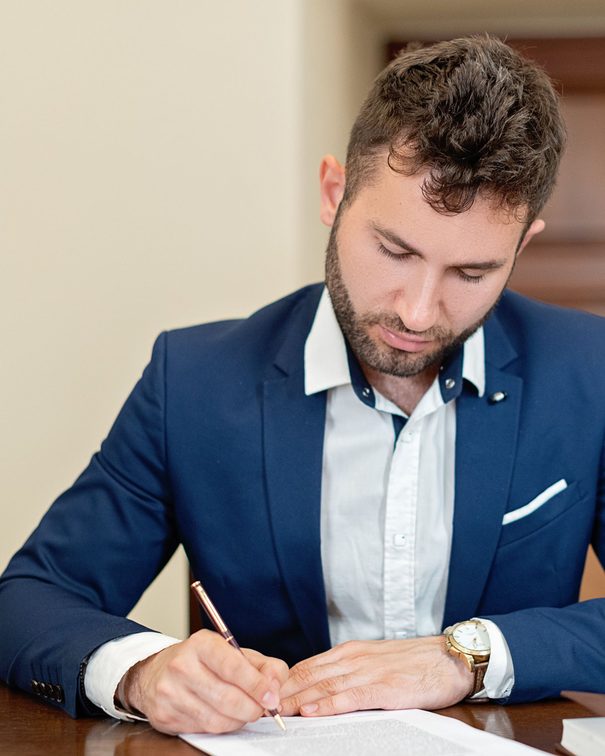 Business professional signing documents at a desk during an advisory meeting.
